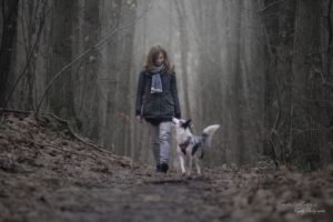 Emilie marche avec son chien au pied dans les bois