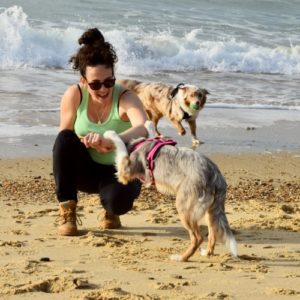 une jeune femme pratique le dog da,cing avec un border collie sur la plage