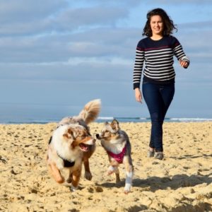 une jeune fille promène 2 chiens sur la plage